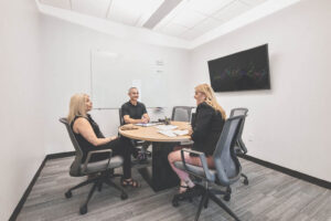 Three employees in a private meeting room.